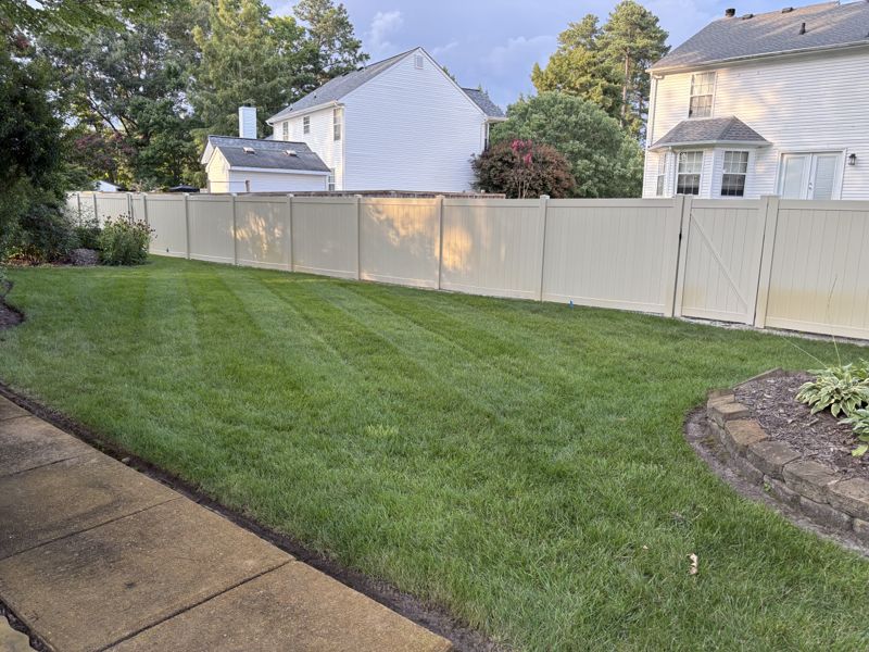 Freshly mowed backyard alongside a white privacy fence