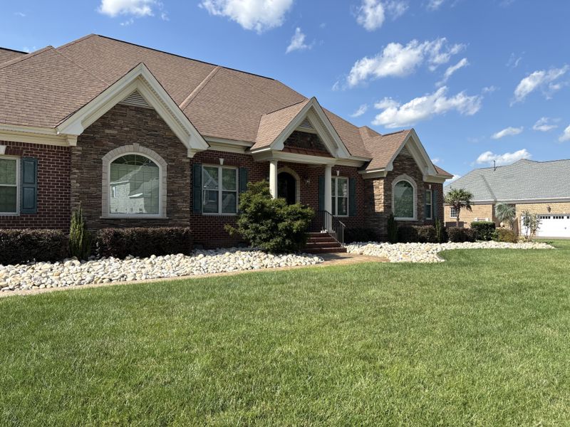 Front lawn and white decorative rock beds outside a brick home