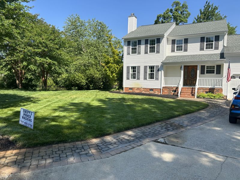 Trimmed front lawn and dark mulch beds beside a brick walkway